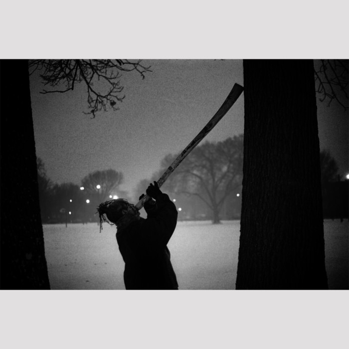 silhouette of man playing didgeridoo in snowy park winter